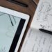 Digital and handwritten brainstorming tools on a wooden desk, ideal for business and study contexts.