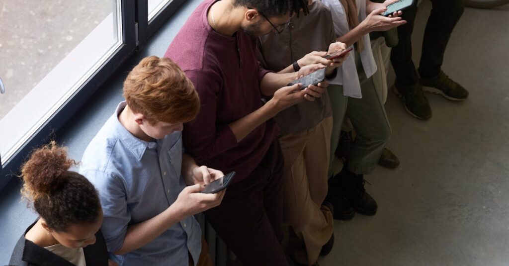 A group of diverse office workers standing by a window using smartphones, capturing modern workplace connectivity.