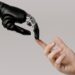 A human hand with tattoos reaching out to a robotic hand on a white background.