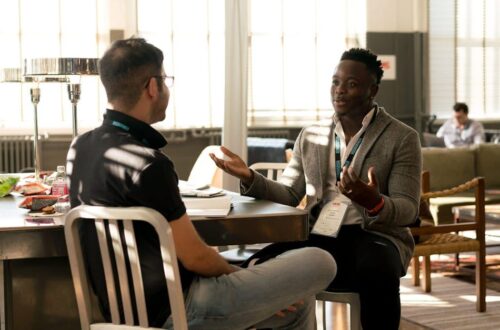 Two men having a casual discussion in a bright indoor setting, highlighting mentorship.