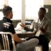 Two men having a casual discussion in a bright indoor setting, highlighting mentorship.